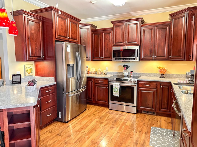 kitchen with light wood-type flooring, stainless steel appliances, reddish brown cabinets, and ornamental molding