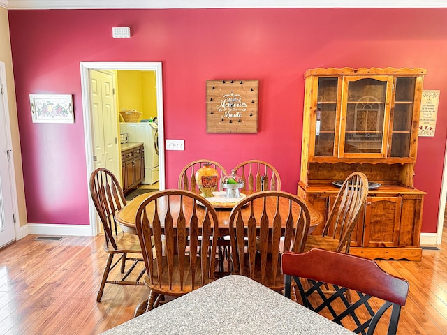 dining area with visible vents, independent washer and dryer, baseboards, and wood-type flooring