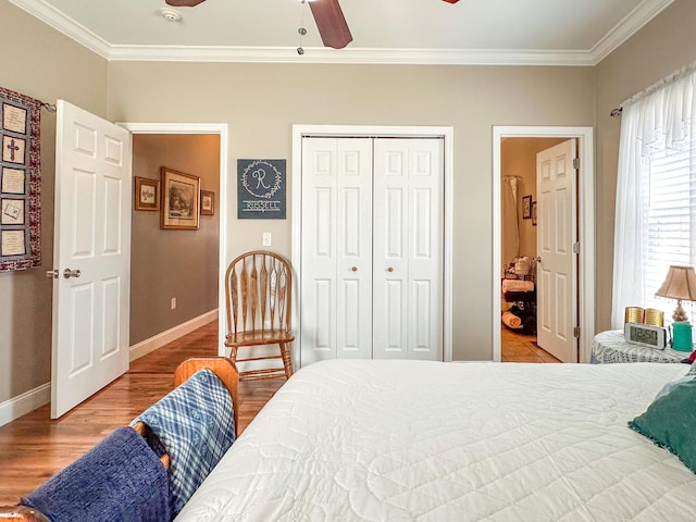 bedroom with wood finished floors, baseboards, ceiling fan, a closet, and crown molding