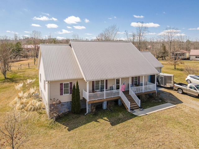 view of front facade featuring a front lawn, stairway, covered porch, and metal roof