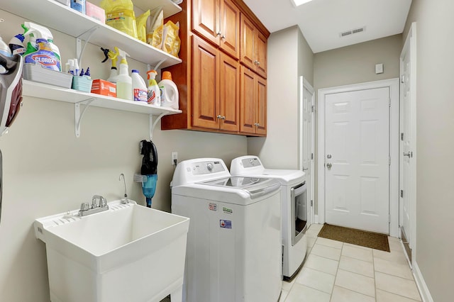 washroom with visible vents, a sink, cabinet space, light tile patterned floors, and washing machine and clothes dryer