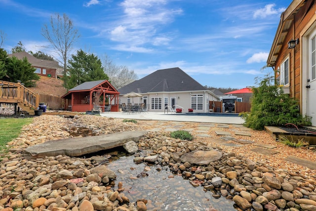 rear view of property featuring a gazebo, a patio area, and fence