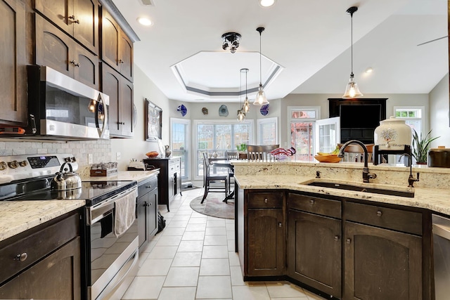 kitchen with pendant lighting, a tray ceiling, a wealth of natural light, appliances with stainless steel finishes, and a sink