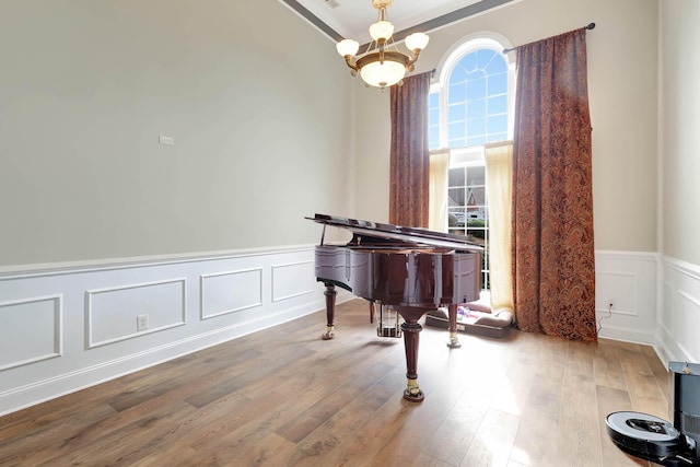 sitting room with an inviting chandelier, a decorative wall, wood finished floors, and wainscoting