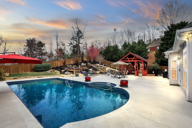 pool at dusk featuring a gazebo, a fenced in pool, and a fenced backyard