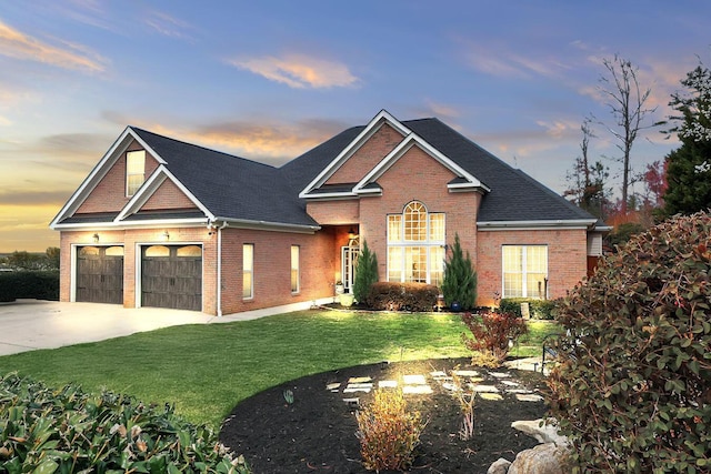 view of front of property with driveway, roof with shingles, a front yard, a garage, and brick siding