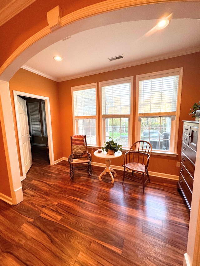 sitting room featuring visible vents, baseboards, arched walkways, dark wood-style flooring, and crown molding