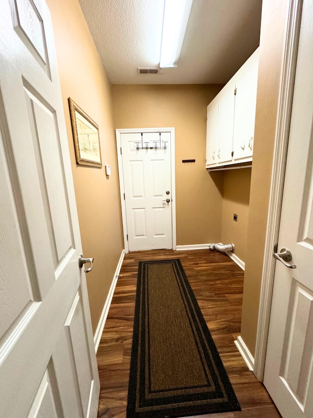 laundry area featuring electric dryer hookup, dark wood-type flooring, a textured ceiling, cabinet space, and baseboards