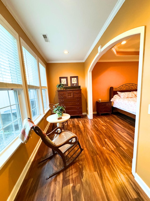 bedroom featuring visible vents, crown molding, baseboards, wood finished floors, and arched walkways