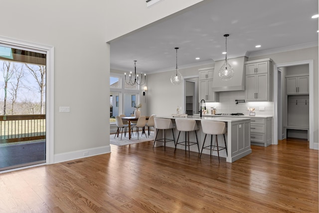 1825 River Breeze Dr, Soddy Daisy, TN 37379 - kitchen featuring wood finished floors, decorative backsplash, light countertops, crown molding, and a kitchen breakfast bar