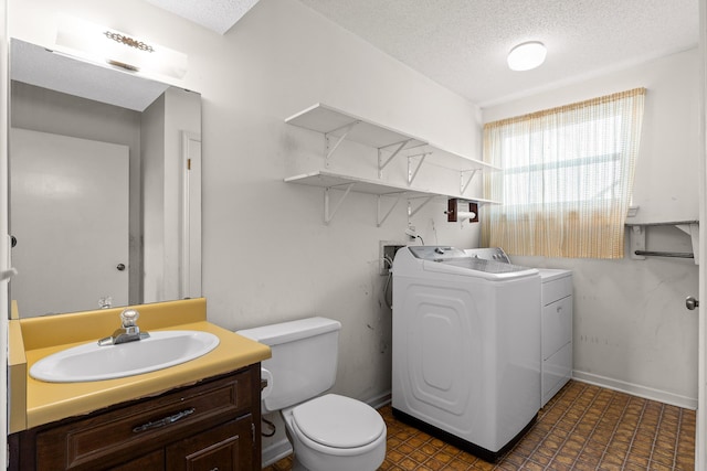 bathroom with independent washer and dryer, a textured ceiling, toilet, and vanity