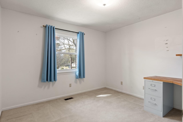 interior space featuring a textured ceiling, baseboards, visible vents, and light carpet