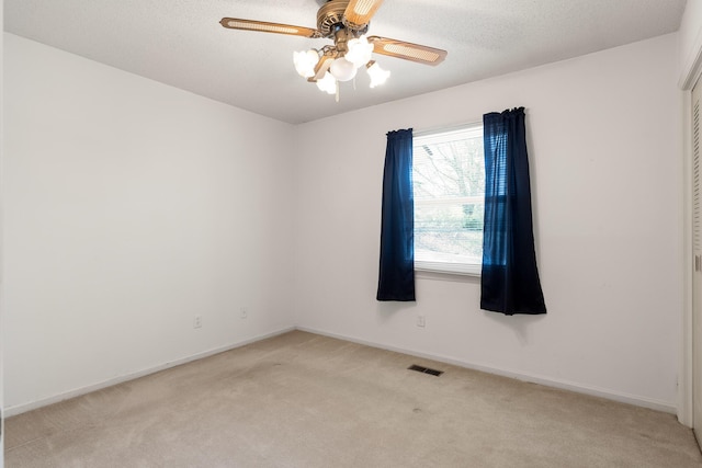 empty room with light carpet, baseboards, a textured ceiling, and a ceiling fan