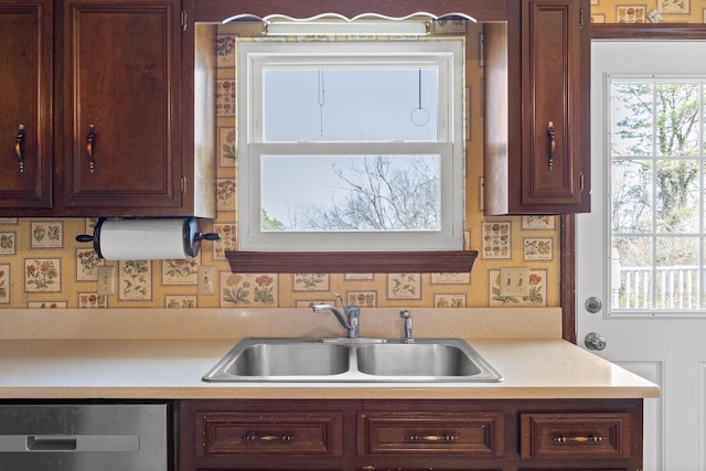 kitchen featuring stainless steel dishwasher, light countertops, and a sink