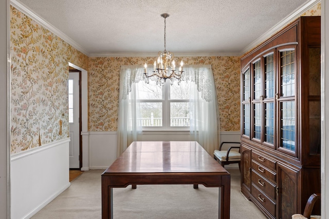 dining room with a textured ceiling, light colored carpet, wainscoting, and wallpapered walls