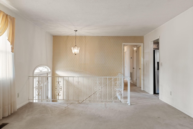 spare room featuring visible vents, light carpet, baseboards, and wallpapered walls