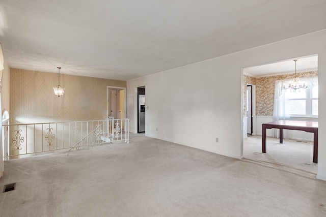 unfurnished room featuring a chandelier, visible vents, wallpapered walls, and carpet floors