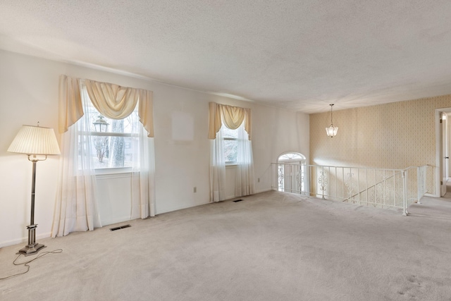 spare room with carpet flooring, visible vents, and a textured ceiling