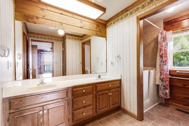 bathroom with wallpapered walls, a shower with shower curtain, and a sink