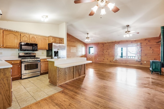 kitchen featuring wooden walls, appliances with stainless steel finishes, light countertops, and a wood stove