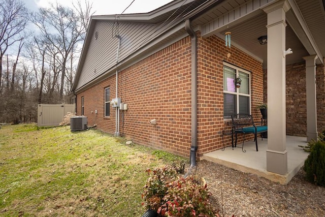 view of property exterior with central air condition unit, brick siding, and a lawn