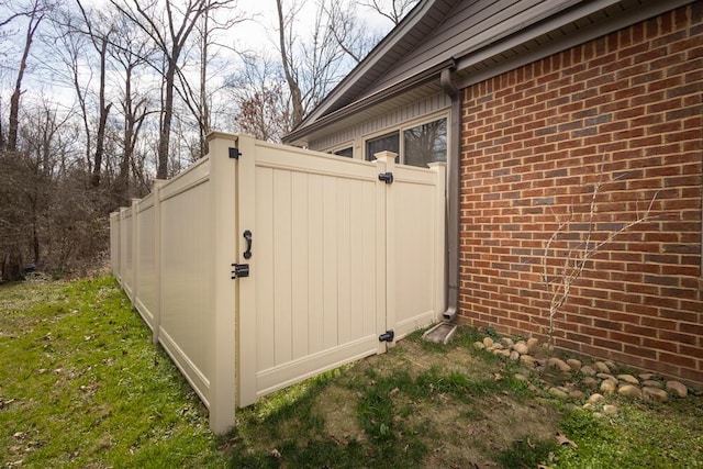 view of property exterior with a gate, fence, and brick siding