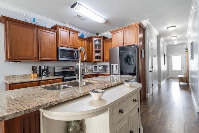 kitchen with visible vents, dark wood-style floors, appliances with stainless steel finishes, brown cabinetry, and crown molding