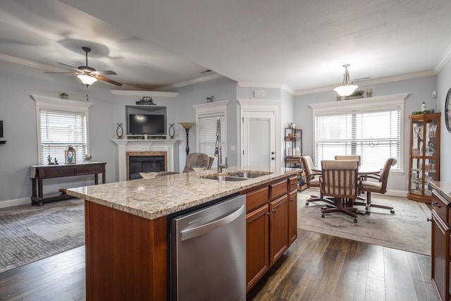 kitchen with brown cabinets, a sink, stainless steel dishwasher, dark wood-style floors, and a glass covered fireplace