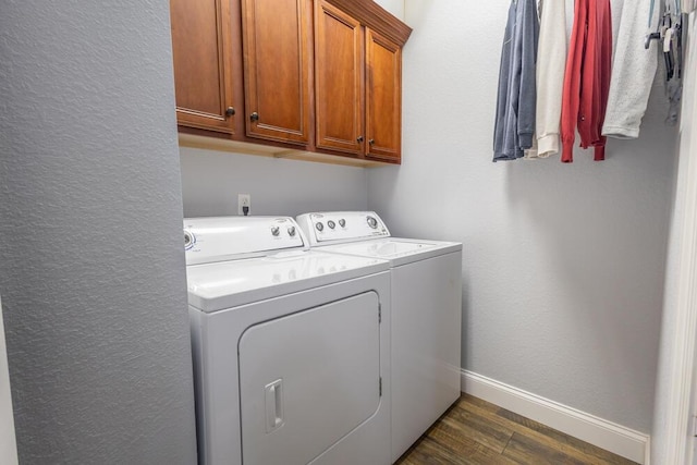 washroom with washing machine and clothes dryer, cabinet space, dark wood-type flooring, and baseboards