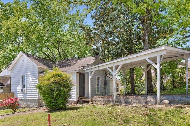 view of front of property featuring a carport, entry steps, a front yard, and roof with shingles