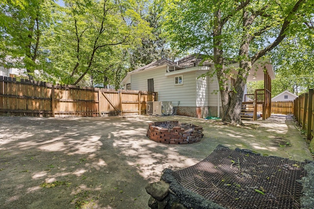 view of yard featuring central air condition unit, a fire pit, a fenced backyard, and a patio area