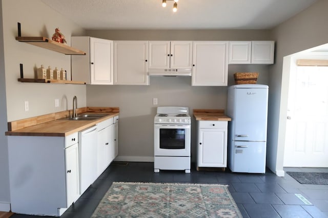 kitchen featuring under cabinet range hood, butcher block counters, white appliances, white cabinetry, and a sink