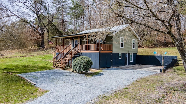 view of front facade featuring gravel driveway, a front yard, stairway, and a porch