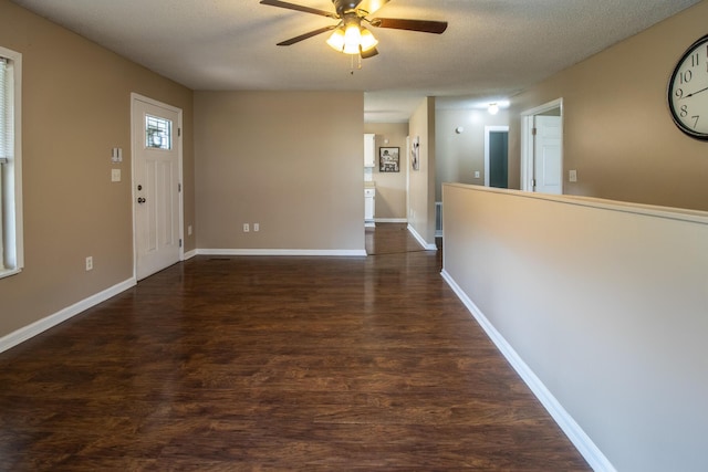 foyer with dark wood-type flooring, a ceiling fan, baseboards, and a textured ceiling