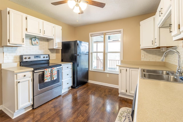 kitchen featuring dark wood-style floors, freestanding refrigerator, a sink, stainless steel range with electric stovetop, and white cabinetry