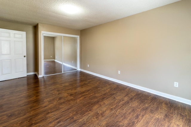 unfurnished bedroom with dark wood finished floors, baseboards, a closet, and a textured ceiling