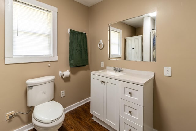 bathroom featuring plenty of natural light, toilet, baseboards, and wood finished floors