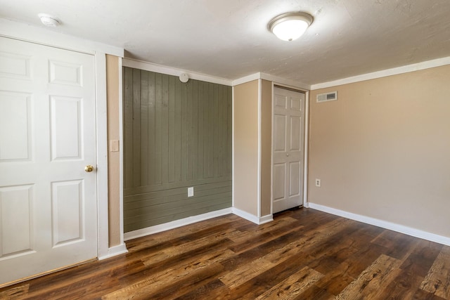 unfurnished bedroom featuring dark wood-style floors, visible vents, and baseboards