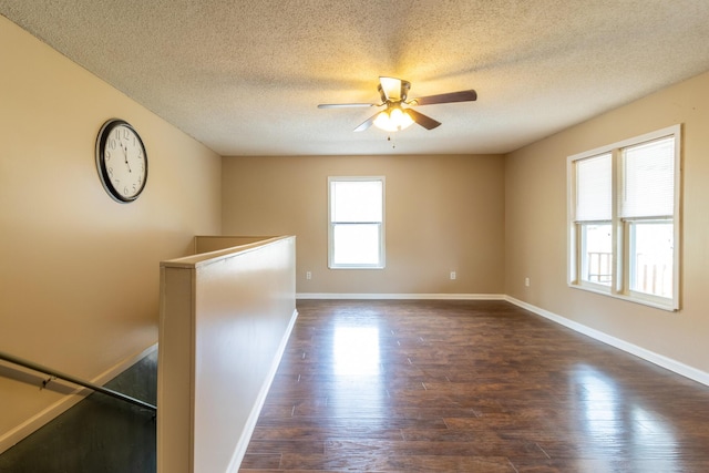 empty room featuring a ceiling fan, dark wood-type flooring, and baseboards