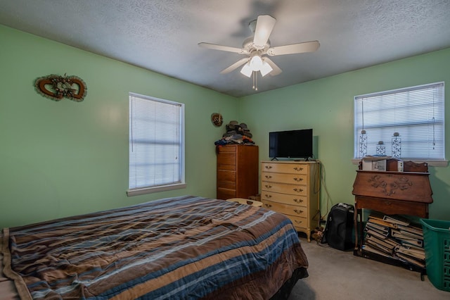 carpeted bedroom with multiple windows, a ceiling fan, and a textured ceiling