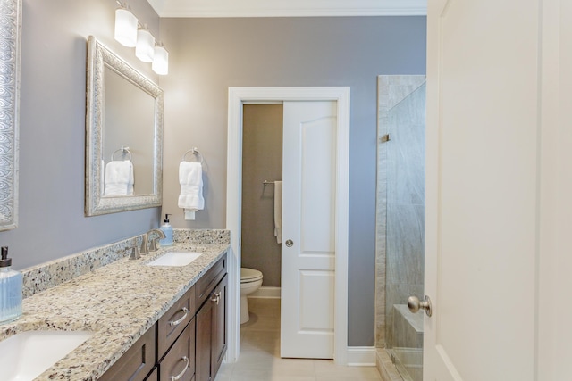 bathroom with a tile shower, double vanity, toilet, and a sink