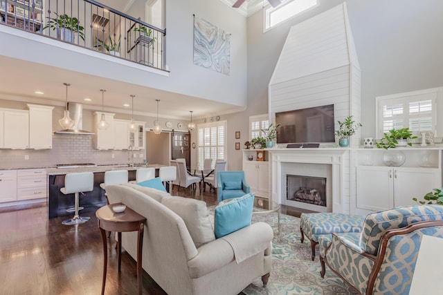 living area with dark wood-style floors, crown molding, and a wealth of natural light