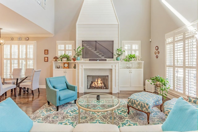 living area with a fireplace, a high ceiling, wood finished floors, and baseboards