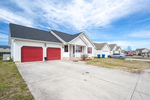 ranch-style home featuring a porch, driveway, an attached garage, and a front lawn