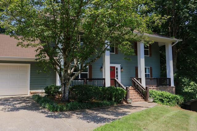 view of front of house featuring an attached garage, a porch, and driveway