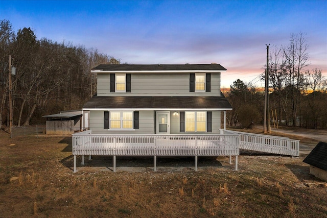 back of house at dusk with a wooden deck