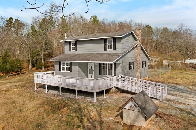 back of property with a wooden deck, a chimney, and fence