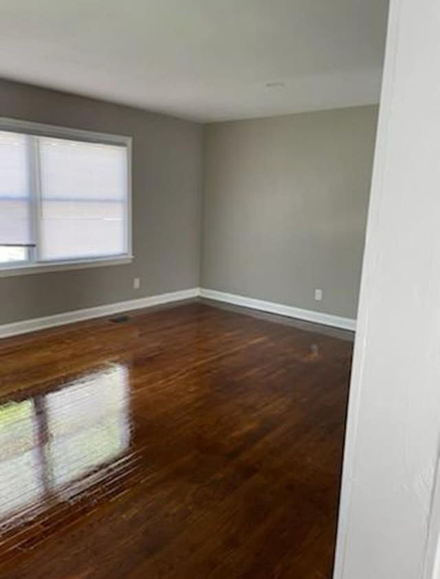 empty room with dark wood-style floors and baseboards