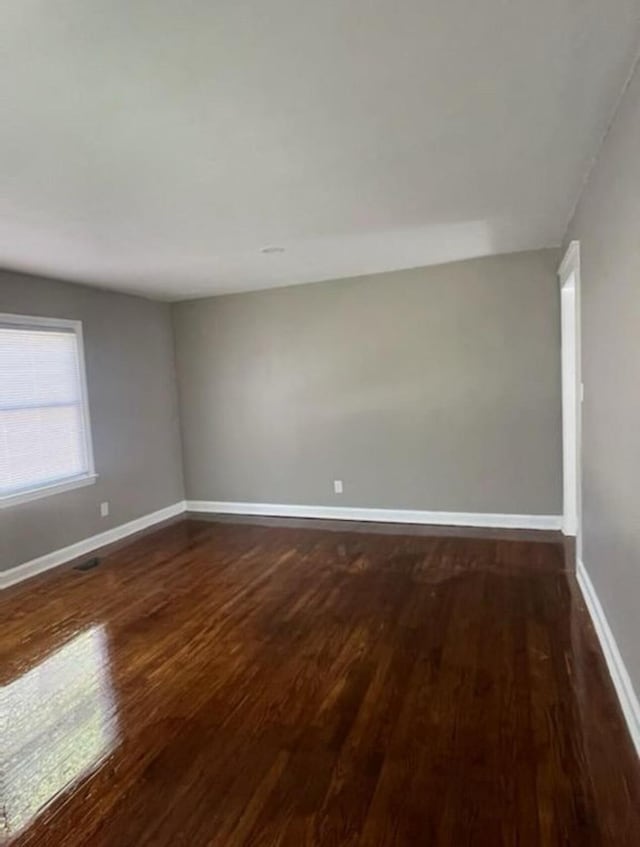 empty room featuring baseboards and dark wood-style flooring