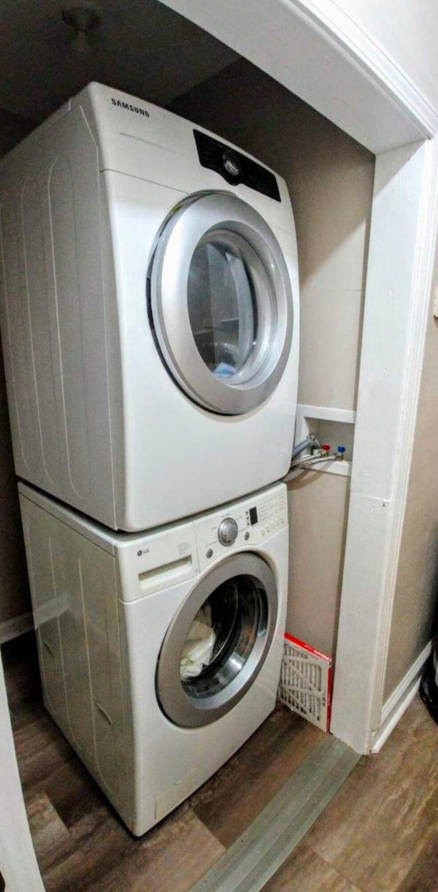 laundry area with laundry area, stacked washing maching and dryer, and wood finished floors